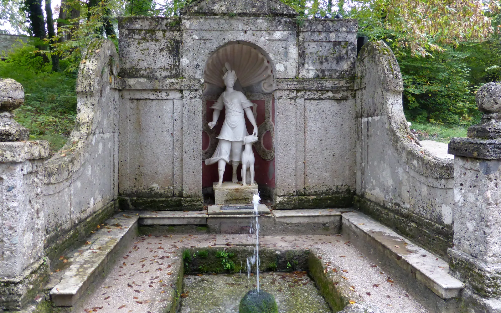 A statue in a stone niche fountain on the Hellbrunn tour