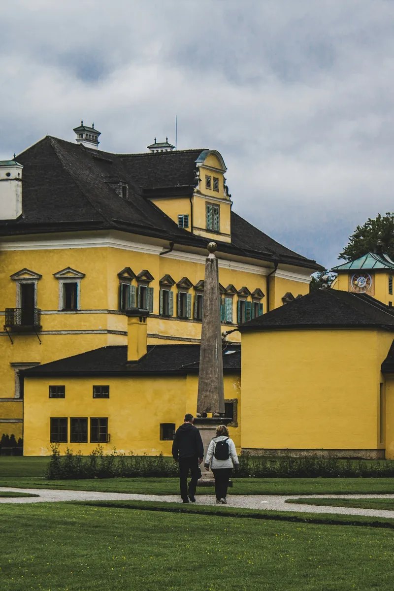 Visitantes riendo mientras surgen chorros ocultos de las fuentes pétreas de los jardines de engaños en el Palacio de Hellbrunn, Salzburgo